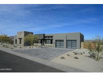 Modern exterior showcasing a contemporary home with a paver driveway and desert landscaping under a blue sky at 12856 E Rosewood Dr, Scottsdale, AZ 85255
