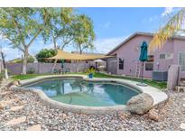A backyard oasis featuring a pebble stone pool, shaded seating, lush landscaping, and a private outdoor retreat at 1774 E Tyson St, Gilbert, AZ 85295