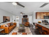 Open living room features a brick fireplace, modern ceiling fans, hardwood floors and stylish leather furniture at 18223 N 20Th Pkwy, Phoenix, AZ 85023