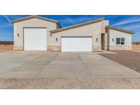 Beautiful three-car garage home exterior with stone veneer and a large concrete driveway on a sunny day at 24032 W Redbird Rd, Wittmann, AZ 85361