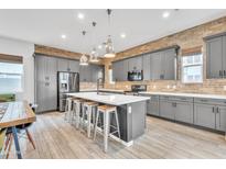 Modern kitchen features grey cabinets, exposed brick backsplash, stainless steel appliances and a large island with seating at 367 N 157Th Ln, Goodyear, AZ 85338