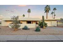 Stunning desert home with unique architecture, lush landscaping, and mature palm trees at 9457 N 80Th Pl, Scottsdale, AZ 85258