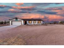 Charming single-story home with a two-car garage and rustic wooden fence under colorful sunset skies at 20438 W Carver Rd, Buckeye, AZ 85326