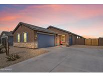 Charming single-story home with desert landscaping, stone accents, and a spacious driveway under a colorful sunset sky at 2466 E Rosario Mission Dr, Casa Grande, AZ 85194