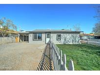 Charming single-story home featuring a gravel yard, white picket fence, and well-maintained front lawn at 3714 E Polk St, Phoenix, AZ 85008