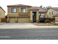 Charming two-story home featuring a three-car garage, tile roof, and landscaped front yard at 5259 W Village Dr, Glendale, AZ 85308