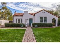 Charming Spanish-style home featuring a brick walkway, manicured lawn, and a distinctive teal front door at 1307 W Palm Ln, Phoenix, AZ 85007