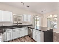 Bright kitchen boasts white cabinetry, stainless steel appliances, and a dark countertop with a breakfast bar at 2402 E 5Th St # 1403, Tempe, AZ 85288