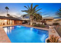 Backyard swimming pool featuring a waterfall, palm tree, and outdoor lounge chairs; perfect for relaxation at 6323 E Gold Dust Ave, Paradise Valley, AZ 85253