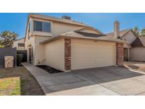 Two-story home with a brick-trimmed, two-car garage and a well-maintained lawn under a bright, cloudless sky at 6405 W Saguaro Dr, Glendale, AZ 85304