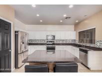 Eat-in kitchen showcasing an island with seating, stainless appliances, and chic mosaic backsplash at 6640 W Honeysuckle Dr, Phoenix, AZ 85083
