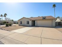 Tan single-story home featuring a two-car garage, low-maintenance desert landscaping, and a basketball hoop above the garage at 10720 E Sahuaro Dr, Scottsdale, AZ 85259