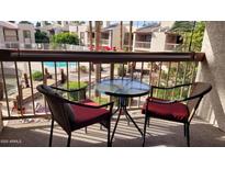 Relaxing balcony seating features a small round glass table and comfortable wicker chairs with views of the community pool and grounds at 205 N 74Th St # 234, Mesa, AZ 85207