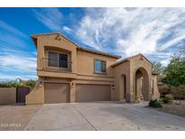 Inviting two-story home featuring a three-car garage, neutral stucco and an arched entrance, under a bright blue sky at 4485 N 152Nd Dr, Goodyear, AZ 85395