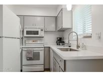 Cozy kitchen features gray cabinets, white appliances, and a stainless steel sink at 4630 N 68Th St # 213, Scottsdale, AZ 85251