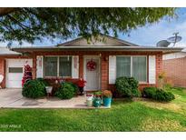 Cozy brick home with a decorative wreath, potted plants, and trimmed green bushes at 10119 N 96Th Ave # B, Peoria, AZ 85345