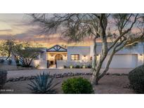 Beautiful home exterior featuring a gated entrance, desert landscaping, and a striking architectural design at sunset at 22619 N La Senda Dr, Scottsdale, AZ 85255