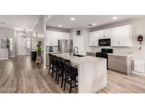 Modern kitchen with a large waterfall island, stainless steel appliances, white cabinets, and wood-look tile flooring at 3765 E Del Rio St, Gilbert, AZ 85295