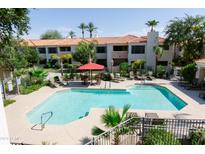 Resort-style community pool with comfortable lounge chairs, a red umbrella, and lush landscaping at 9990 N Scottsdale Rd # 2049, Paradise Valley, AZ 85253