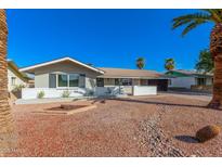 Charming single-story home features a low white brick wall, desert landscaping and mature palm trees at 1206 E Loyola Dr, Tempe, AZ 85282