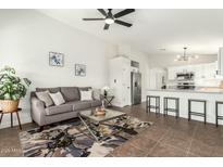 Open concept living room featuring a gray sofa, modern ceiling fan, and seamless flow into the kitchen area at 13267 W Port Au Prince Ln, Surprise, AZ 85379