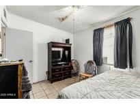 Modest bedroom featuring a bed, TV cabinet, and natural light from a window at 1813 W Tamarisk St, Phoenix, AZ 85041