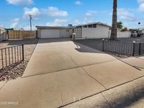 Traditional single-story home featuring an attached garage, mature palm tree, and a spacious concrete driveway at 6633 W Orange Dr, Glendale, AZ 85301