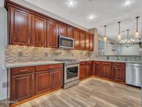 Kitchen with stainless steel appliances, wood cabinets, and mosaic backsplash at 6847 W Palo Brea Ln, Peoria, AZ 85383