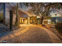 Inviting front exterior featuring a desert landscape, lush tree, and a charming brick driveway at 24201 N 87Th St, Scottsdale, AZ 85255