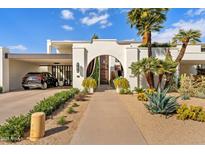 Stunning modern home with desert landscaping, arched entryway, and a covered carport at 7242 E Joshua Tree Ln, Scottsdale, AZ 85250