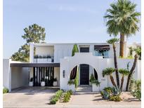 Elegant two-story home with a charming archway, lush landscaping, and a covered carport at 7242 E Joshua Tree Ln, Scottsdale, AZ 85250