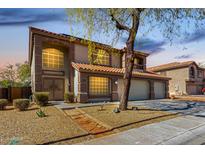 Two-story home with an attached three-car garage, desert landscaping, and a decorative stone pathway to the front door at 100 N 221St Ave, Buckeye, AZ 85326