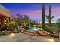 Backyard pool and hot tub with desert landscaping, boulders, and stone steps create a tranquil outdoor space at 10639 E Mark Ln, Scottsdale, AZ 85262