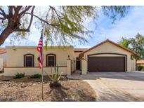 Charming single-story home with a well-maintained front yard, two-car garage and gated front door, all beneath a sunny, blue sky at 1133 E Juanita Ave, Gilbert, AZ 85234