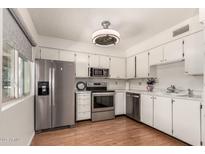 Bright kitchen features stainless steel appliances, white cabinetry, and wood-look flooring at 2442 E University Dr # 6, Mesa, AZ 85213