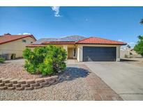 Charming single-story home with a tile roof, solar panels, and desert landscaping at 7102 W Julie Dr, Glendale, AZ 85308