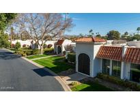 Charming street view featuring well-maintained lawns, white homes with Spanish tile roofs, and manicured bushes at 7121 E Mcdonald Dr, Paradise Valley, AZ 85253