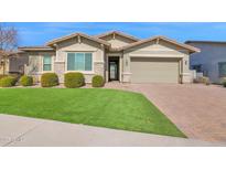 Charming home featuring a well-manicured lawn, brick driveway, and a two-car garage on a sunny day at 13734 W Harvest Ave, Litchfield Park, AZ 85340