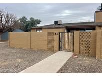 Tan block wall with a gated entry and walkway to this residential home at 3646 N 67Th Ave # 83, Phoenix, AZ 85033