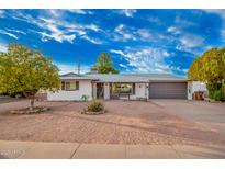 Charming single-story home with low maintenance desert landscaping and a gray two car garage door at 5725 E Colby St, Mesa, AZ 85205