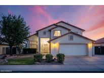 Charming two-story home featuring a two car garage, desert landscaping, and a tile roof at dusk at 16161 W Monte Cristo Ave, Surprise, AZ 85374