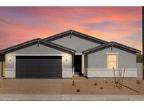 Charming single-story home featuring a two-car garage, neutral paint, and desert landscaping set against a vibrant sunset sky at 4812 W Hunter Trl, San Tan Valley, AZ 85144