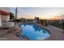 Resort-style pool featuring a waterfall, privacy landscaping, and desert views at sunset at 6188 N 29Th Pl, Phoenix, AZ 85016