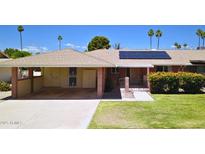 Single story home featuring a covered carport, solar panels, and a well-maintained front lawn with flowering bushes at 10816 W Venturi Dr, Sun City, AZ 85351
