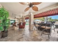 Covered patio featuring comfortable seating, a ceiling fan, and beautiful stone pillars at 14266 W Kiowa Trl, Surprise, AZ 85374