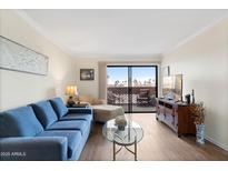 Bright living room features a comfortable blue sofa and sliding doors to a private balcony with views at 4141 N 31St St # 405, Phoenix, AZ 85016