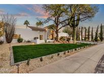 Charming front yard with lush green grass, desert landscaping, and a white stucco home exterior at 8713 N 80Th Pl, Scottsdale, AZ 85258