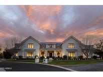 Beautiful light-colored brick home with a symmetrical facade, illuminated against a colorful twilight sky at 20406 E Sunset Ct, Queen Creek, AZ 85142