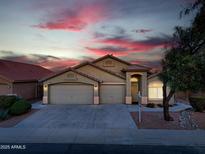 Charming single-story home with three-car garage and desert landscaping at sunset at 22139 N Van Loo Dr, Maricopa, AZ 85138