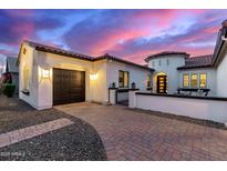 Charming home featuring a terracotta roof, a two-car garage, and decorative stonework, all under a colorful twilight sky at 8418 W Louise Ct, Peoria, AZ 85383